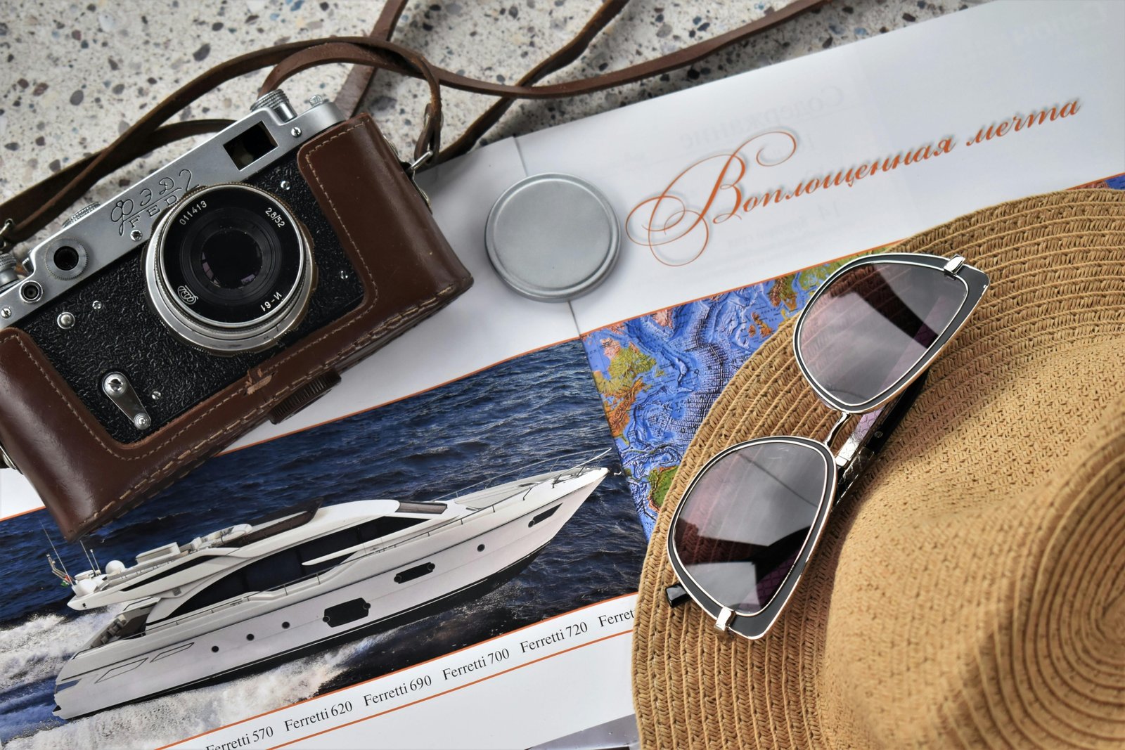 Luxury travel accessories including designer luggage, silk travel pillow, noise-cancelling headphones, and RFID-blocking wallet arranged in a stylish flat lay