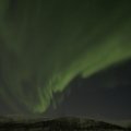 Northern Lights over snowy Finnish landscape in winter with forests and mountains