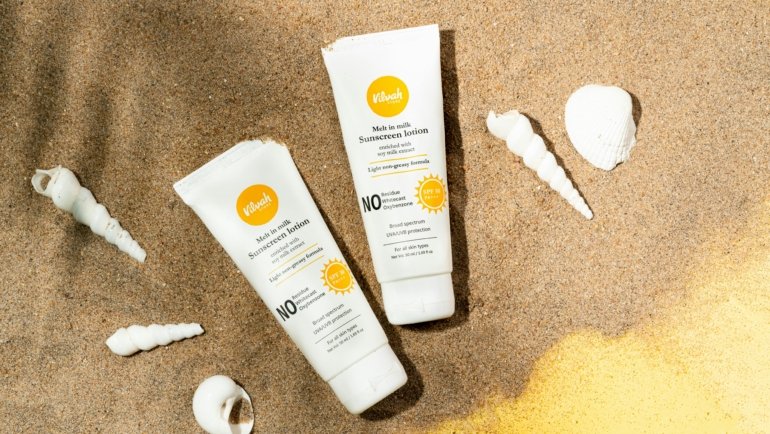 Sun Bum travel size sunscreen and lip balm with travel essentials on a sunny beach for convenient and eco-friendly sun protection