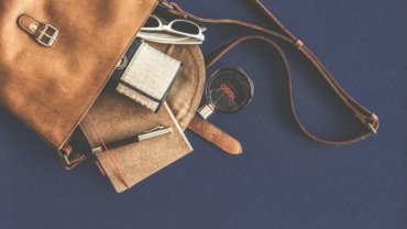 Luxury travel accessories including designer luggage, leather passport holders, noise-canceling headphones, and skincare kit for sophisticated travelers