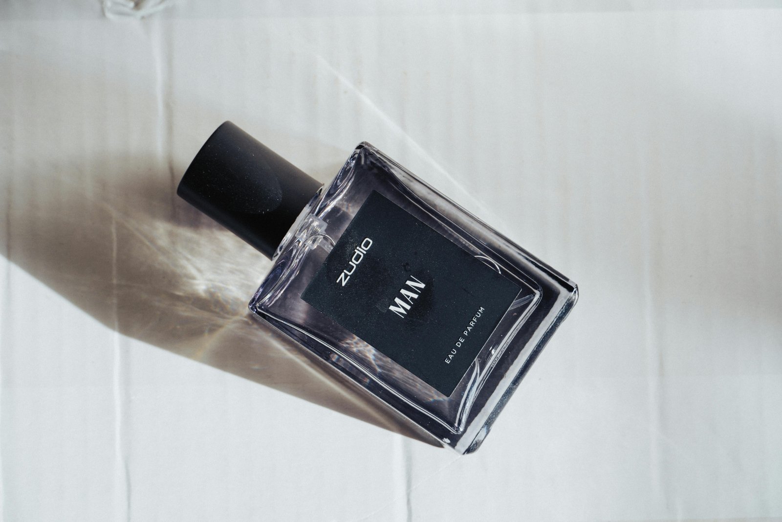 Compact cologne travel spray bottle next to passport and sunglasses for easy freshening on the go