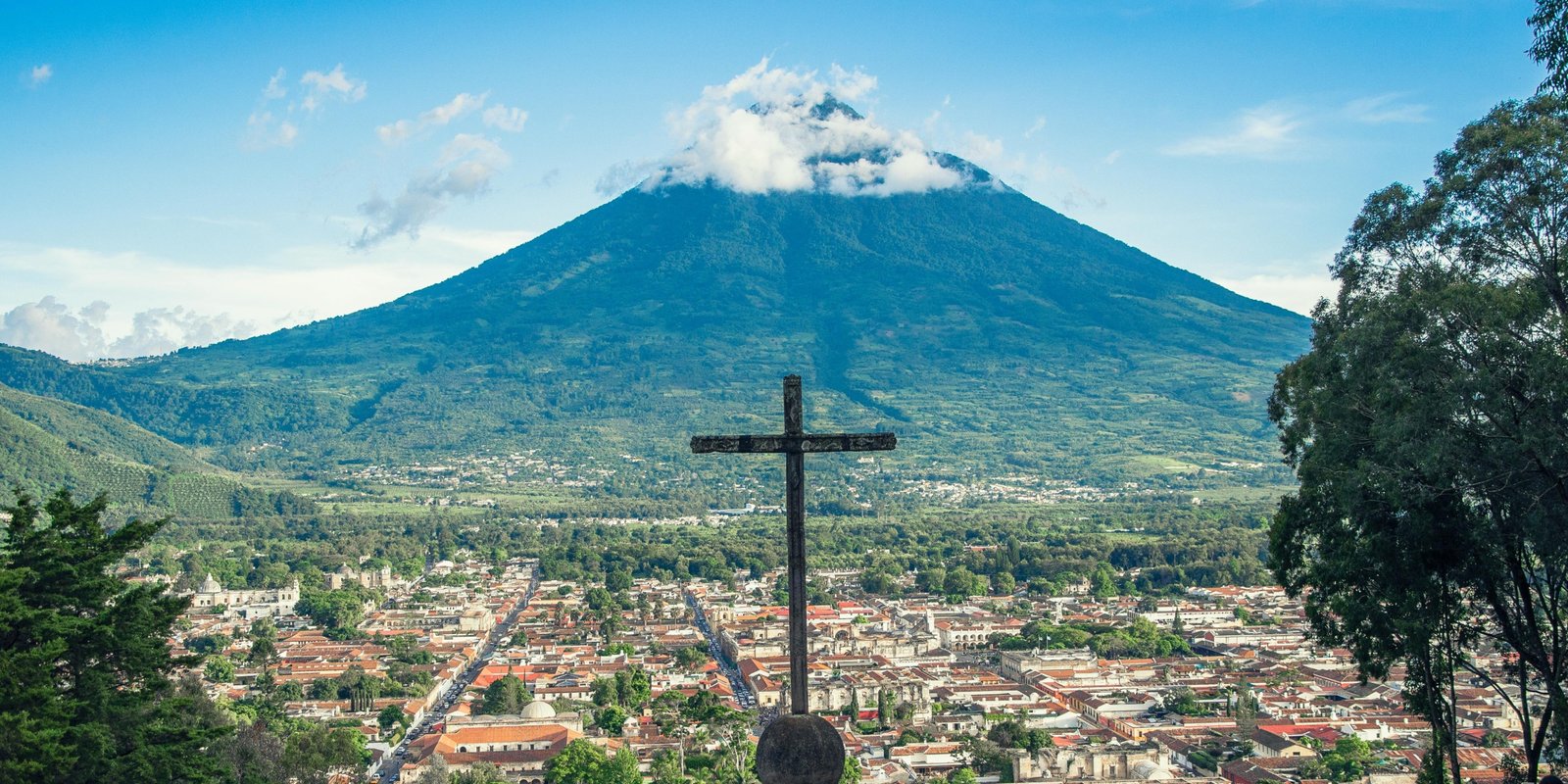 Scenic view of Guatemala volcano with cultural market and ancient ruins, ideal for travel and tourism packages