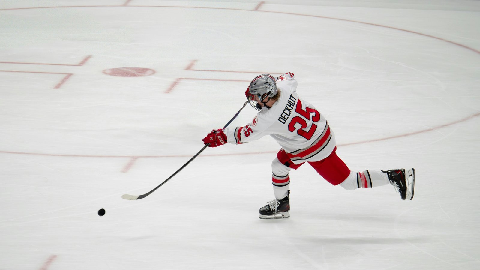 Hockey puck flying at high speed across smooth ice during a professional game