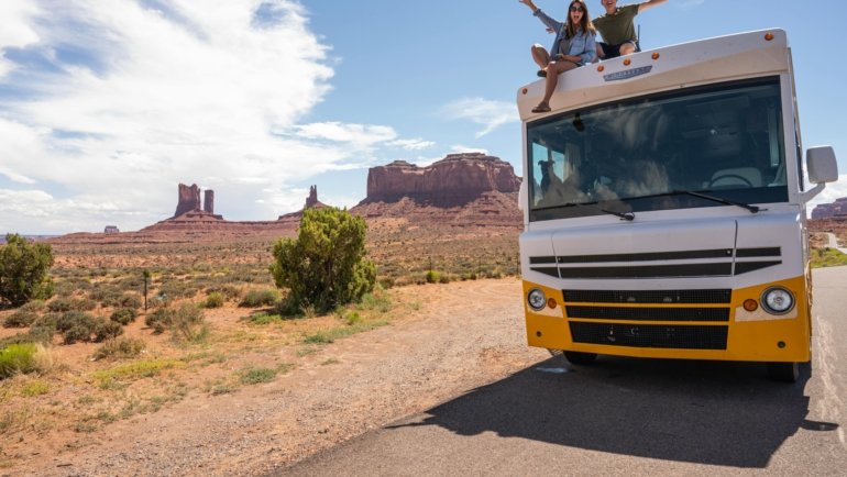 Family enjoying a road trip beside a modern RV in a beautiful outdoor landscape, representing happy and comfortable travel with Happy Traveler RV