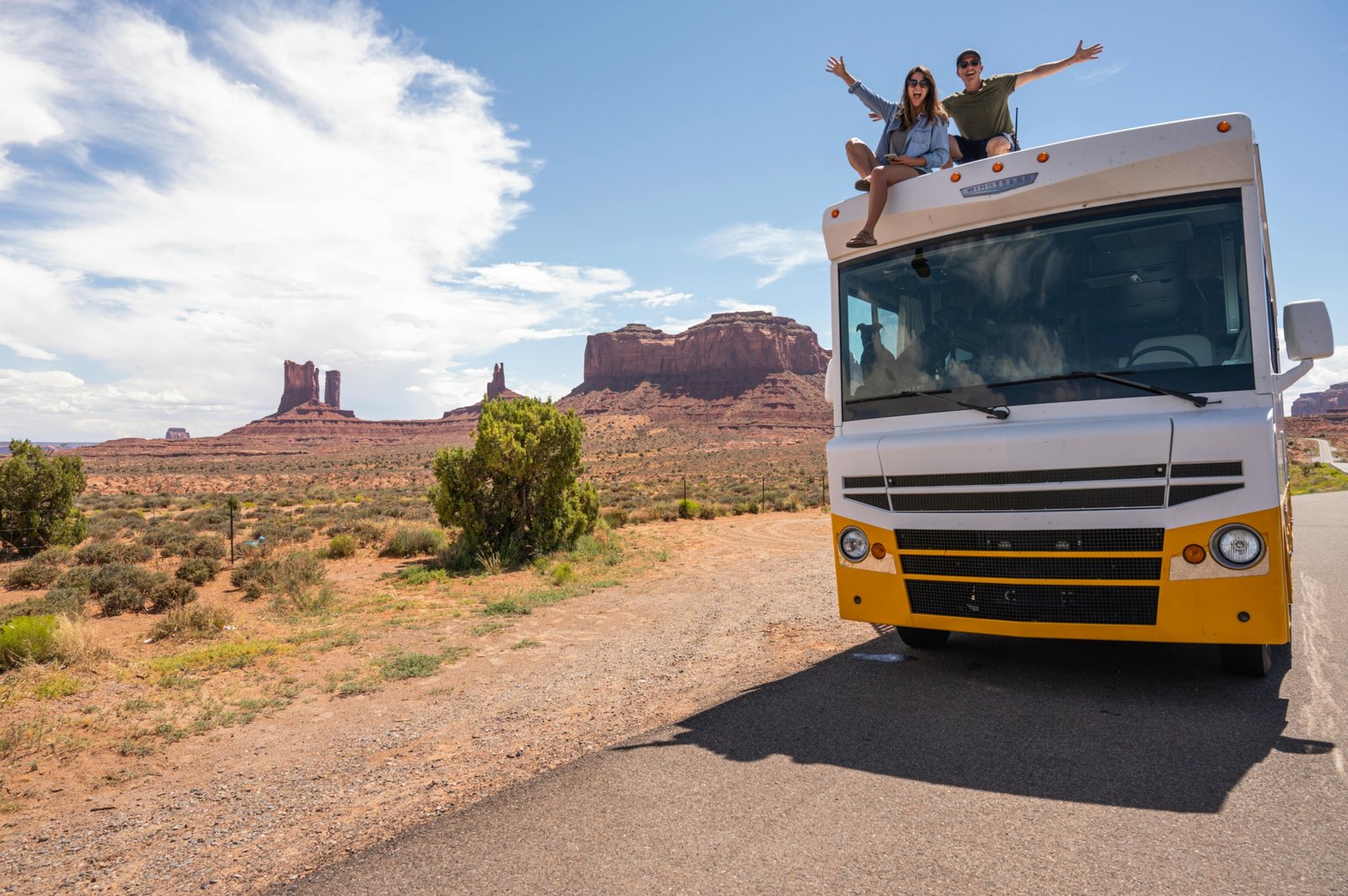 Family enjoying a road trip beside a modern RV in a beautiful outdoor landscape, representing happy and comfortable travel with Happy Traveler RV