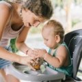 Infant sitting securely in a portable travel high chair outdoors during family travel