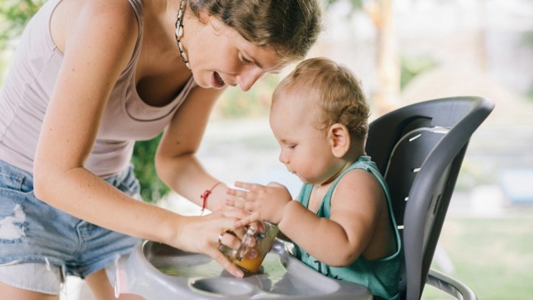 Infant sitting securely in a portable travel high chair outdoors during family travel