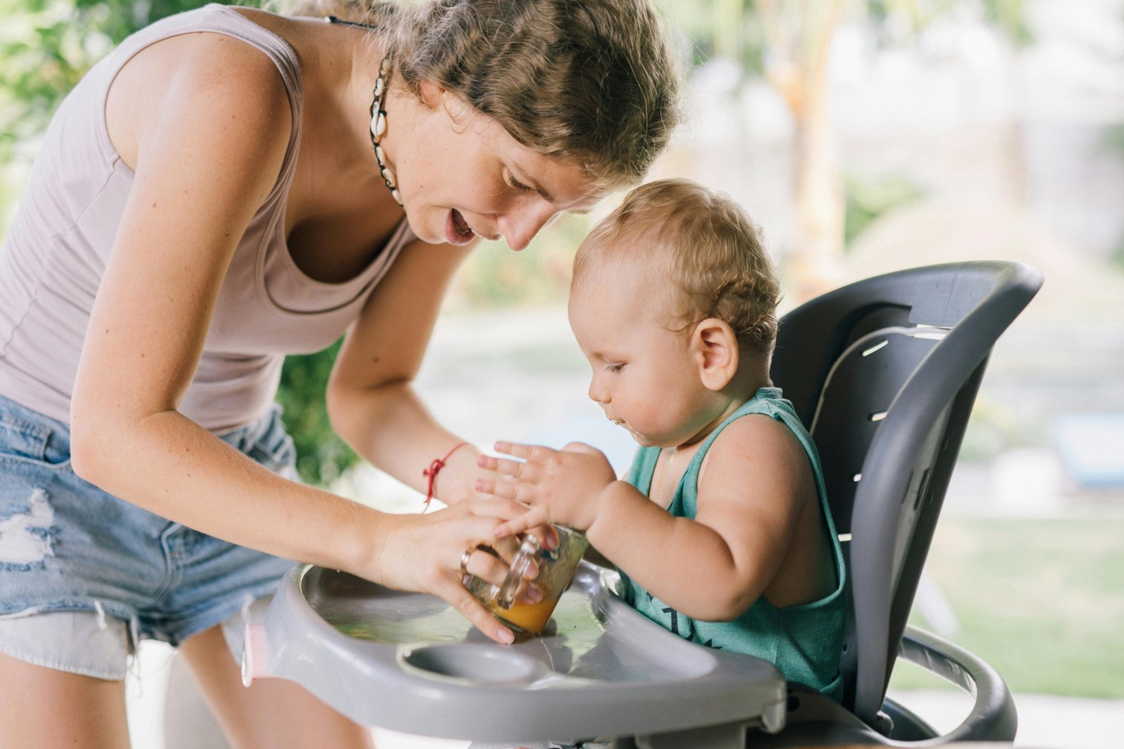 Infant sitting securely in a portable travel high chair outdoors during family travel