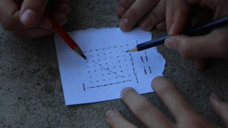 Person solving literary crossword puzzle with classic novel Gulliver's Travels open nearby