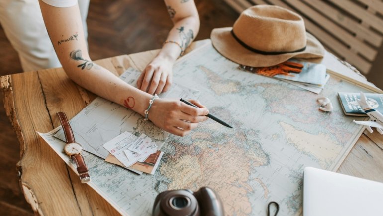 Smiling travelers planning their vacation with a travel agent using maps and laptops for a stress-free trip