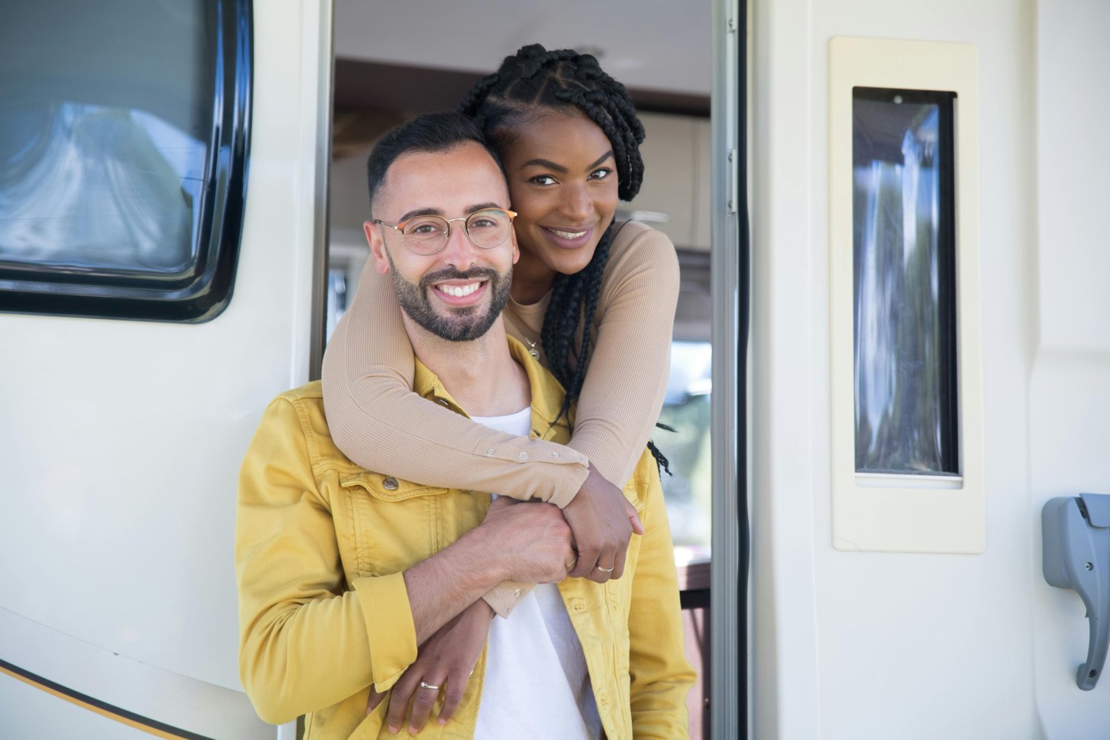 Couple relaxing outside a compact travel trailer during a camping trip in nature