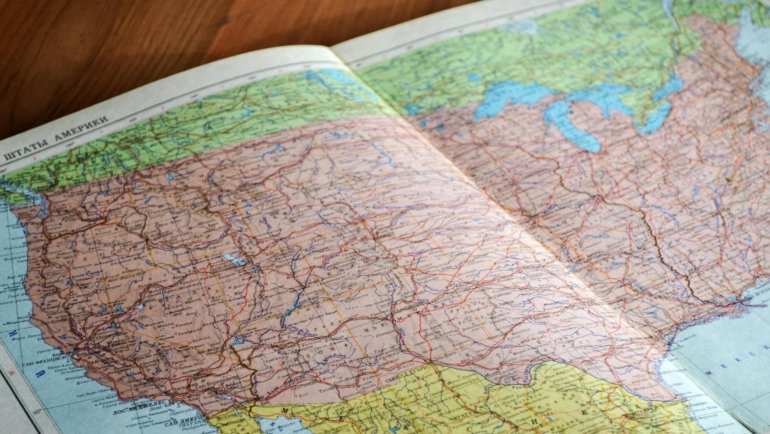 US wall travel map decorated with colorful pins marking visited states and cities representing travel memories and adventures