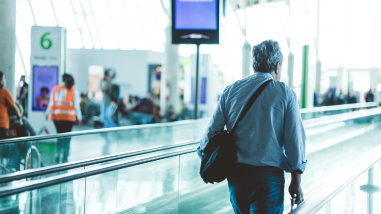Man wearing wrinkle-resistant travel sport coat with pockets at airport, demonstrating style and comfort for business travel
