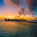 Stunning tropical beach at sunset with clear lagoon and luxurious overwater bungalows in an exotic travel destination