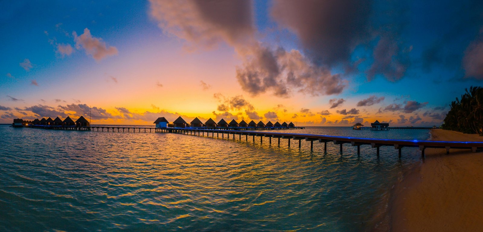 Stunning tropical beach at sunset with clear lagoon and luxurious overwater bungalows in an exotic travel destination