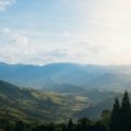 Travel nurse in scrubs standing in front of Alaskan mountains and wilderness, representing Alaska travel RN jobs combining nursing and adventure