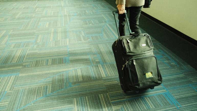 Traveler pulling wheeled duffle bag through airport terminal with ease