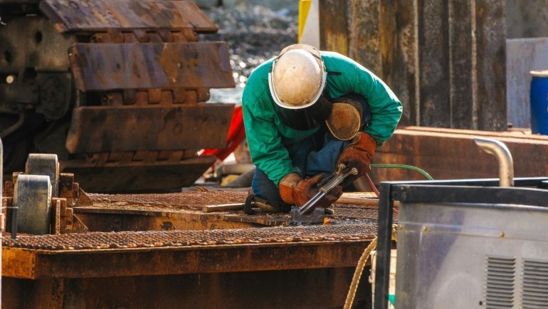 travel welder working on metal construction site outdoors with safety gear