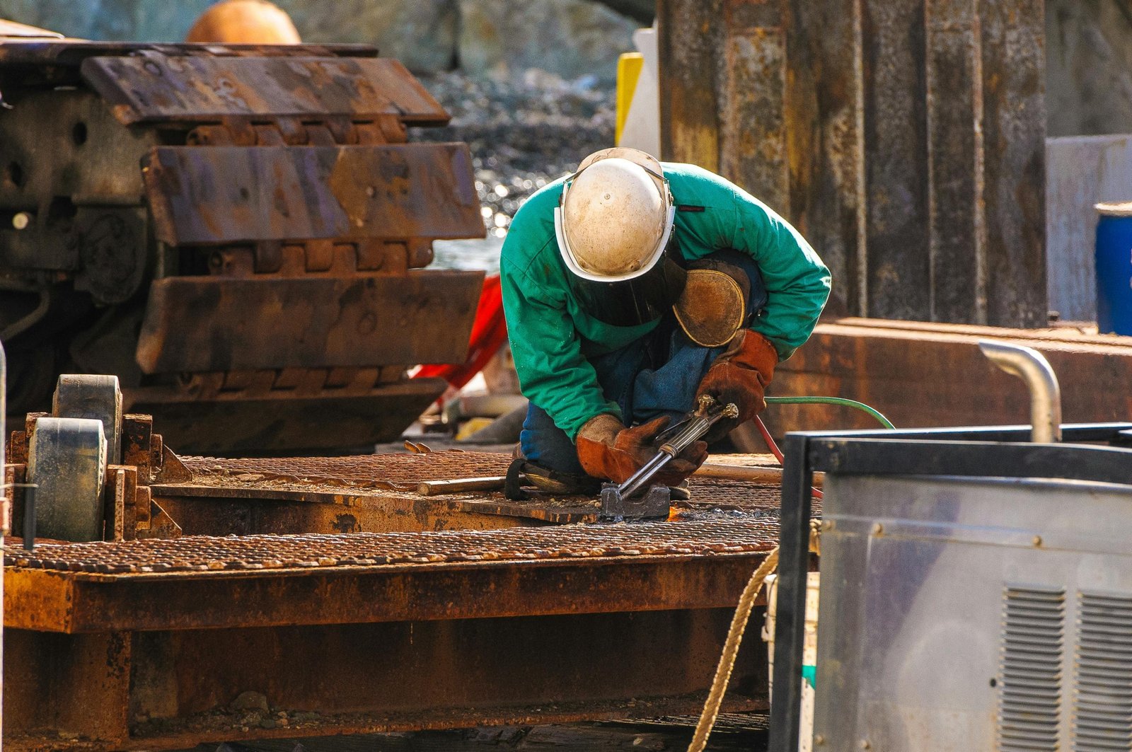 travel welder working on metal construction site outdoors with safety gear
