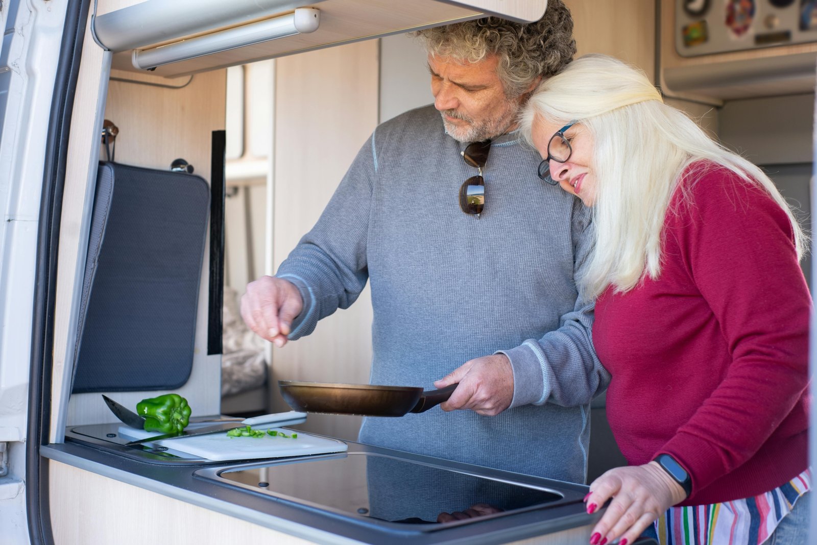 Modern travel trailer kitchen with compact stove oven cooking home-cooked meal on the road