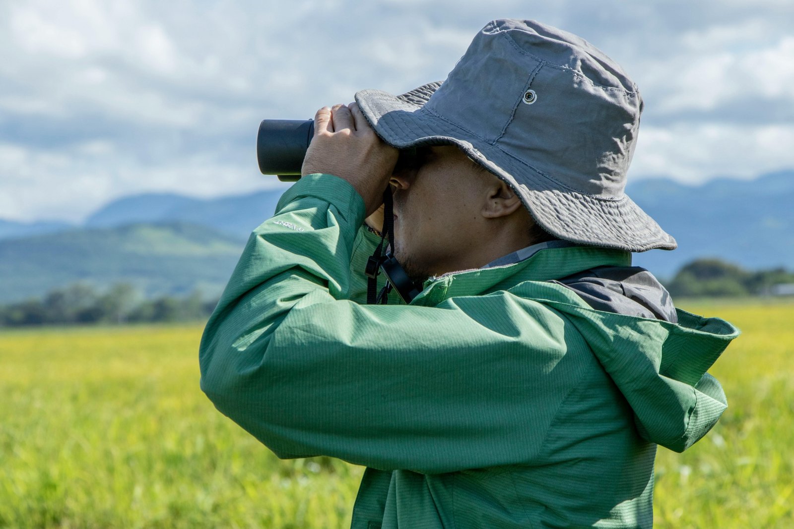 Traveler looking through compact travel binoculars in a natural setting, enjoying clear and detailed views of wildlife and scenery