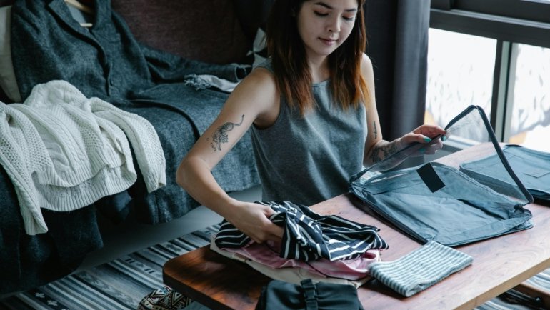 Woman packing wrinkle-free travel dress into suitcase for wrinkle-free stylish and comfortable travel