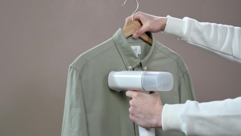 Compact travel fabric steamer packed in luggage for wrinkle-free clothes while traveling