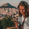 Traveler happily using a smartphone with travel apps to navigate and plan a stress-free trip