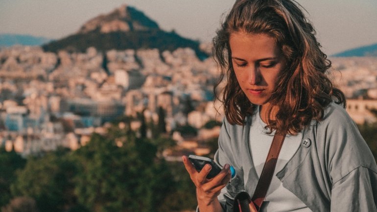 Traveler happily using a smartphone with travel apps to navigate and plan a stress-free trip