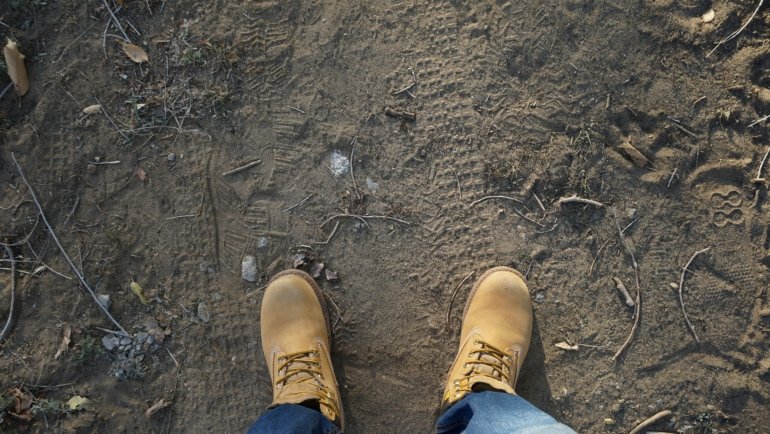 Durable travel boots worn by a traveler walking on a rugged outdoor trail, perfect for hiking and urban exploration