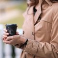 Personalized travel coffee cup held outdoors by traveler, reusable and eco-friendly beverage container