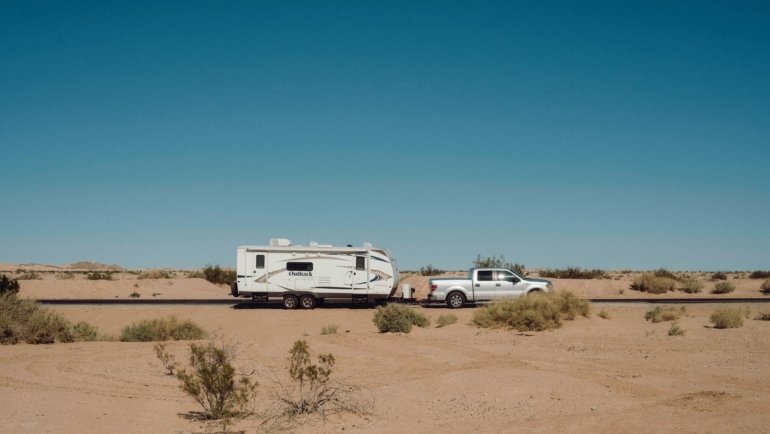 Truck towing a travel trailer on a scenic road demonstrating towing capability and adventure