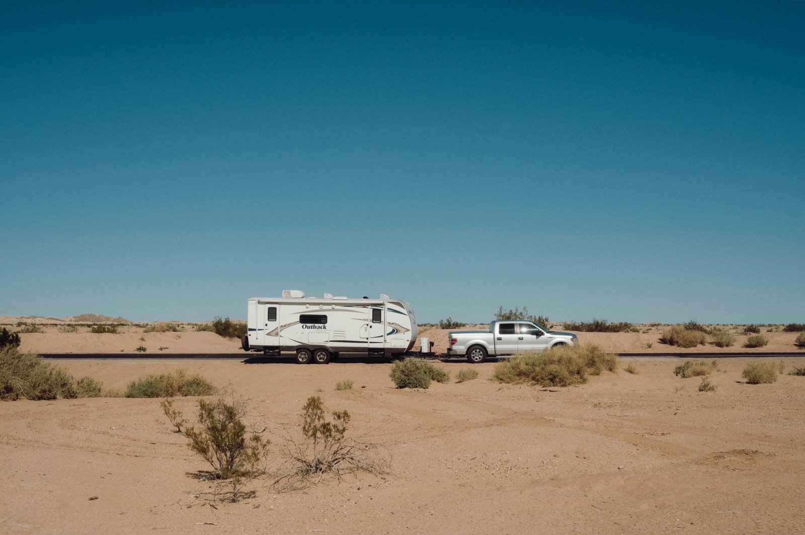 Truck towing a travel trailer on a scenic road demonstrating towing capability and adventure