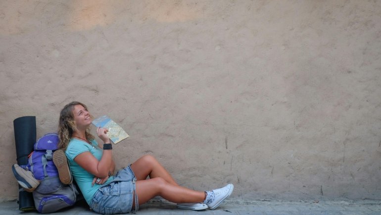 Traveler with backpack looking at a map outdoors, representing flexible and spontaneous luna travel style