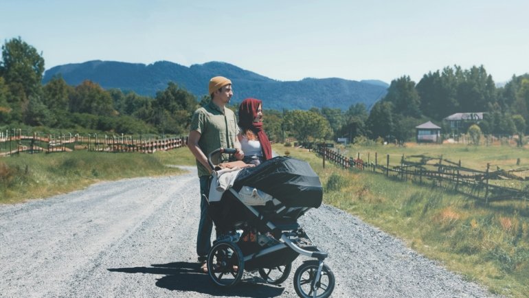 Parent pushing baby in safe and comfortable Chicco travel system stroller outdoors