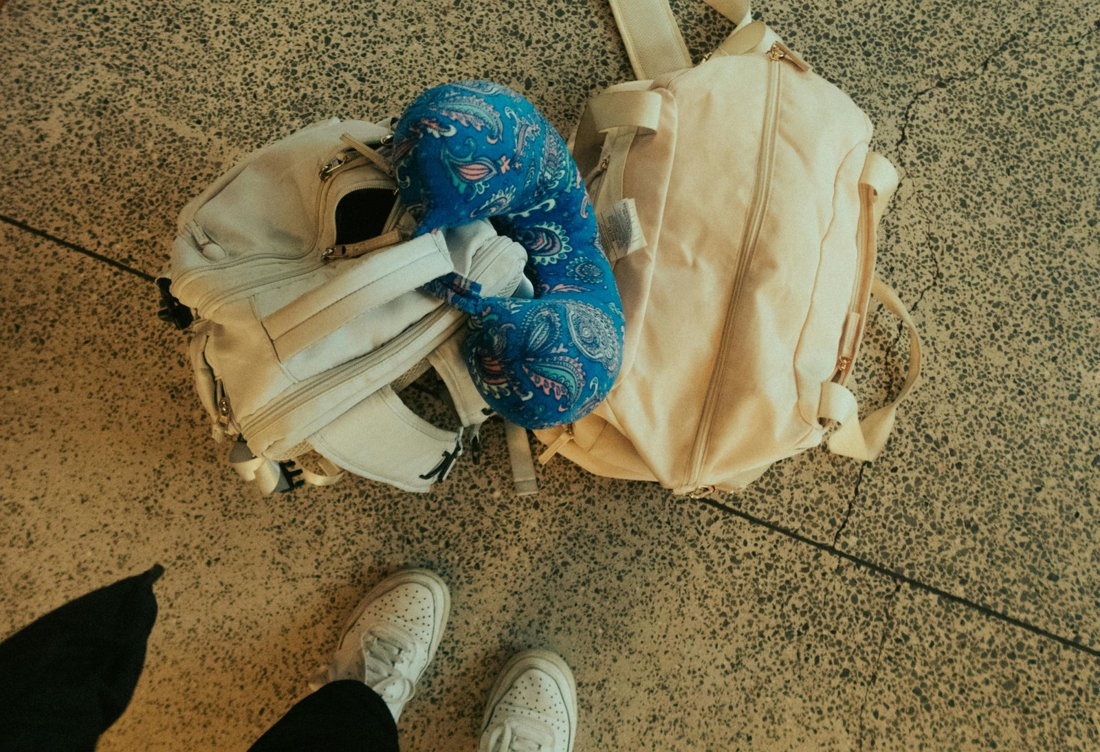 Traveler with a compact travel pillow bag attached to suitcase at airport for organized and comfortable journey
