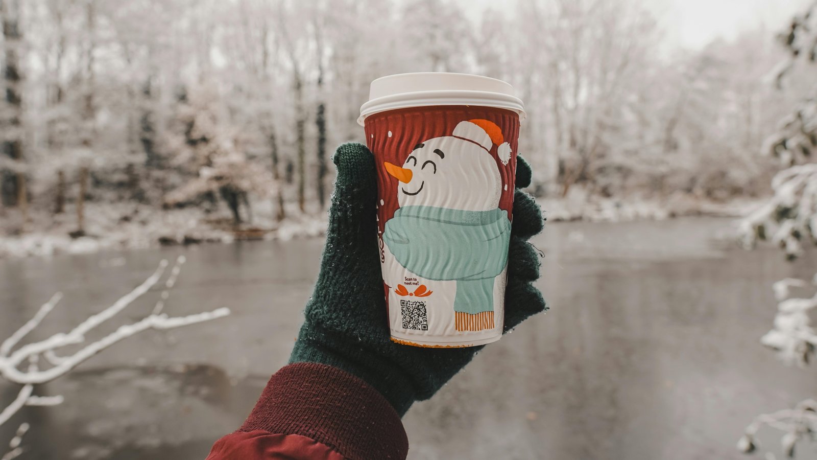 Christmas themed travel coffee mug with festive design held outdoors in winter