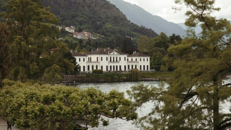 Beautiful springtime view of Lake Como with blooming gardens and calm blue waters under clear skies