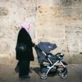 Lightweight travel stroller folded and carried by parent during family trip outdoors