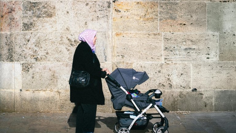 Lightweight travel stroller folded and carried by parent during family trip outdoors