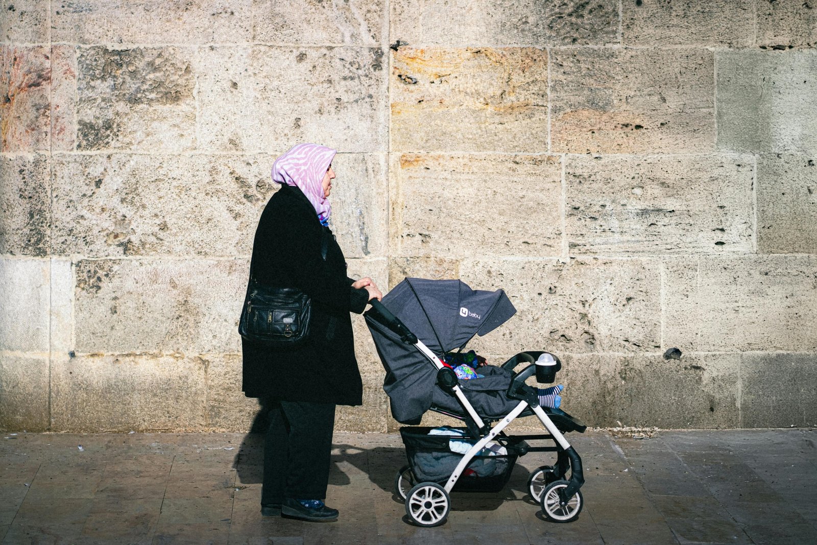 Lightweight travel stroller folded and carried by parent during family trip outdoors