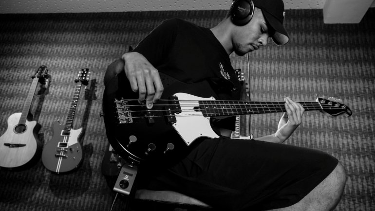 Bass player carrying a hard case bass guitar while traveling for music performances