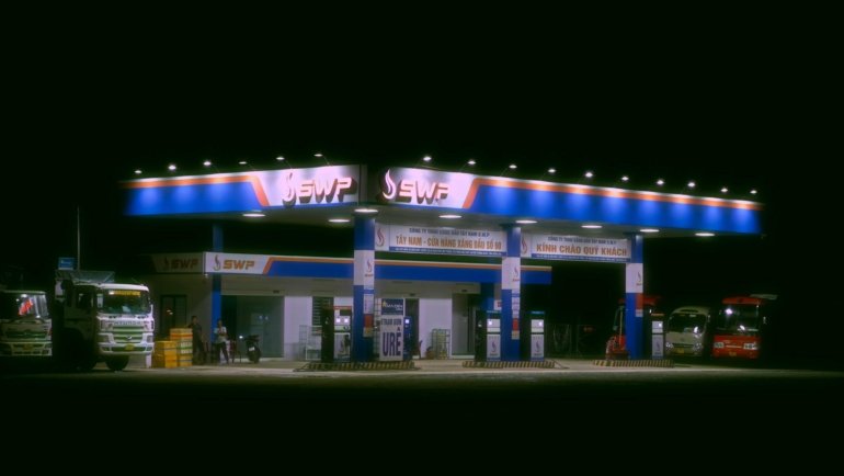 Roadster travel center and truck stop with fuel pumps, parked vehicles, convenience store, and resting travelers near highway