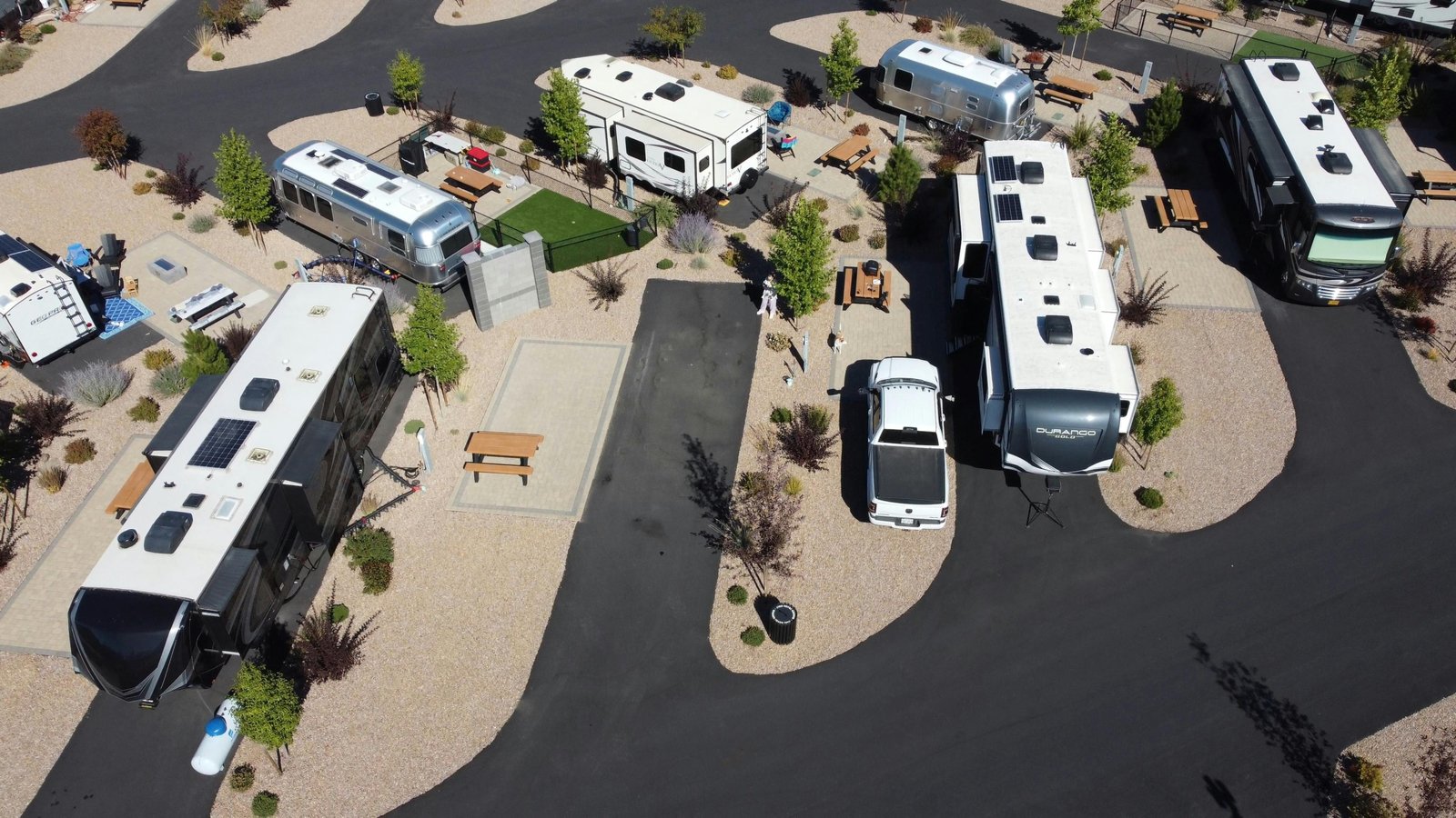 Comparison of fifth wheel and travel trailer RVs parked in nature showing different towing styles and spacious layouts for outdoor camping