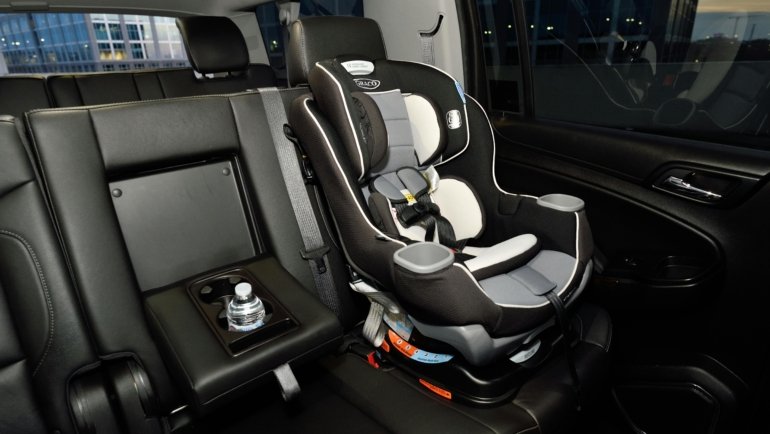 Rear facing travel car seat installed in a car with child safely secured, highlighting safety and comfort
