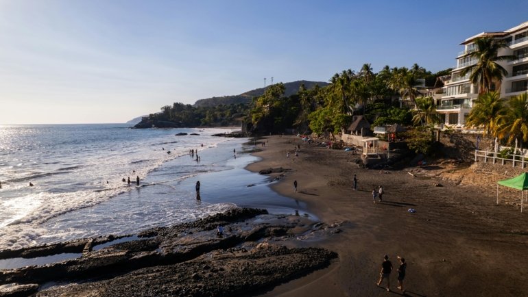 Sunny El Salvador beach with surfers and clear blue sky during the dry season