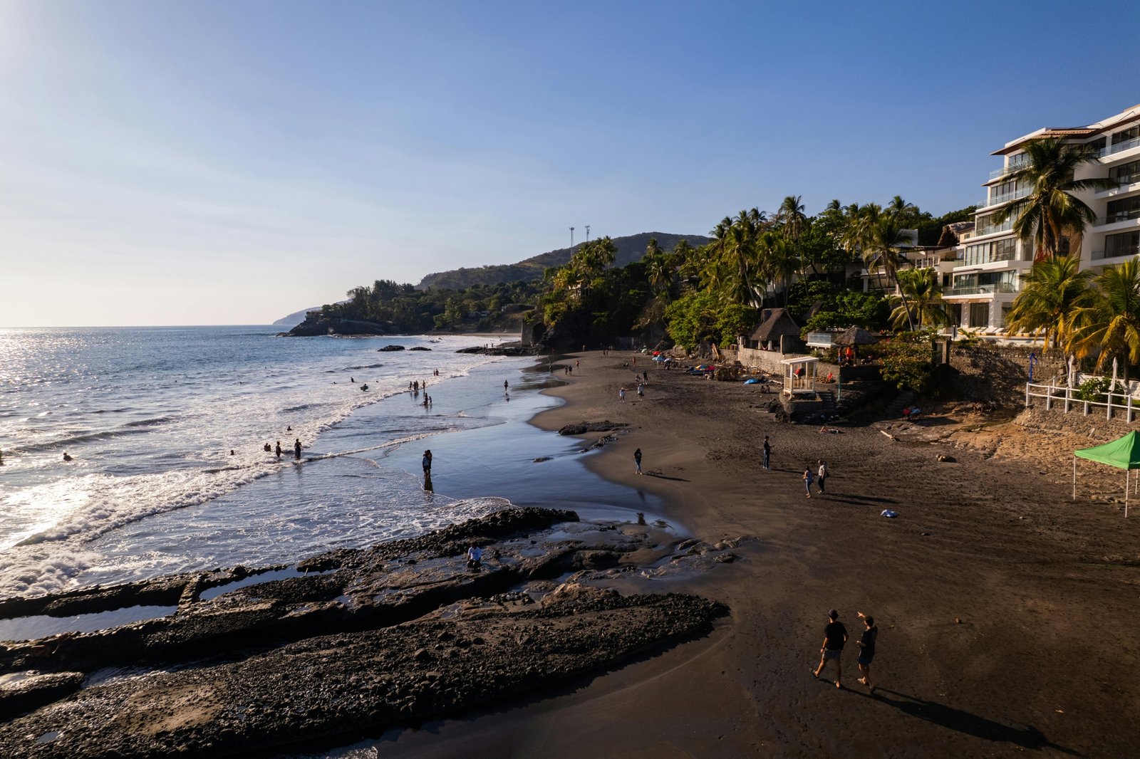 Sunny El Salvador beach with surfers and clear blue sky during the dry season