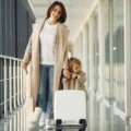 Parent wheeling a child's car seat on a travel cart through an airport for easy family travel