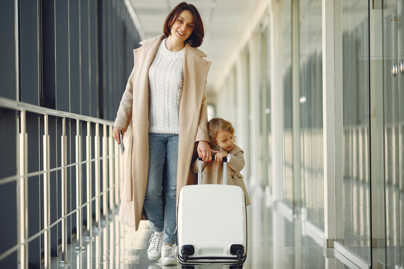 Parent wheeling a child's car seat on a travel cart through an airport for easy family travel