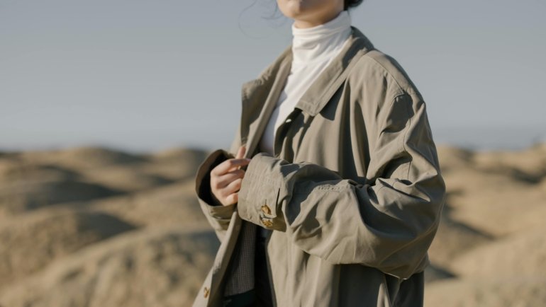 Traveler wearing a waterproof and insulated travel coat outdoors, illustrating durability and comfort in variable weather conditions